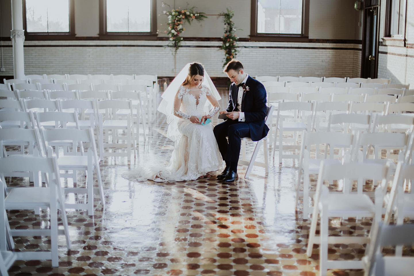 Couple in the light-filled indoor ceremony space with tall arched windows and mosaic tile floors at 1899 Events